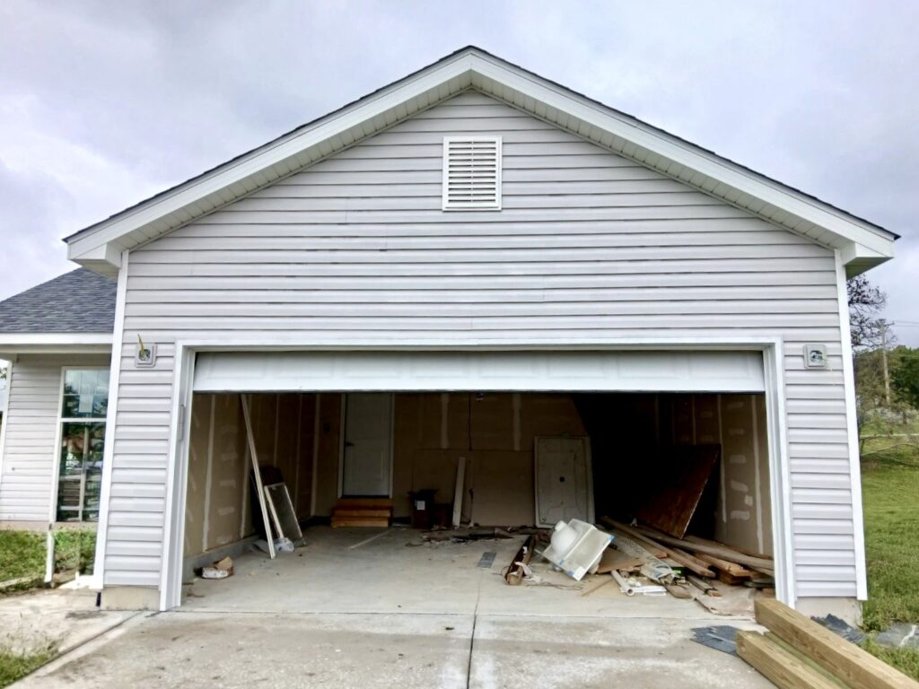 New vinyl siding installation in progress on a Belleville IL home with white lap siding and dark asphalt shingles by Barringer Brothers Roofing